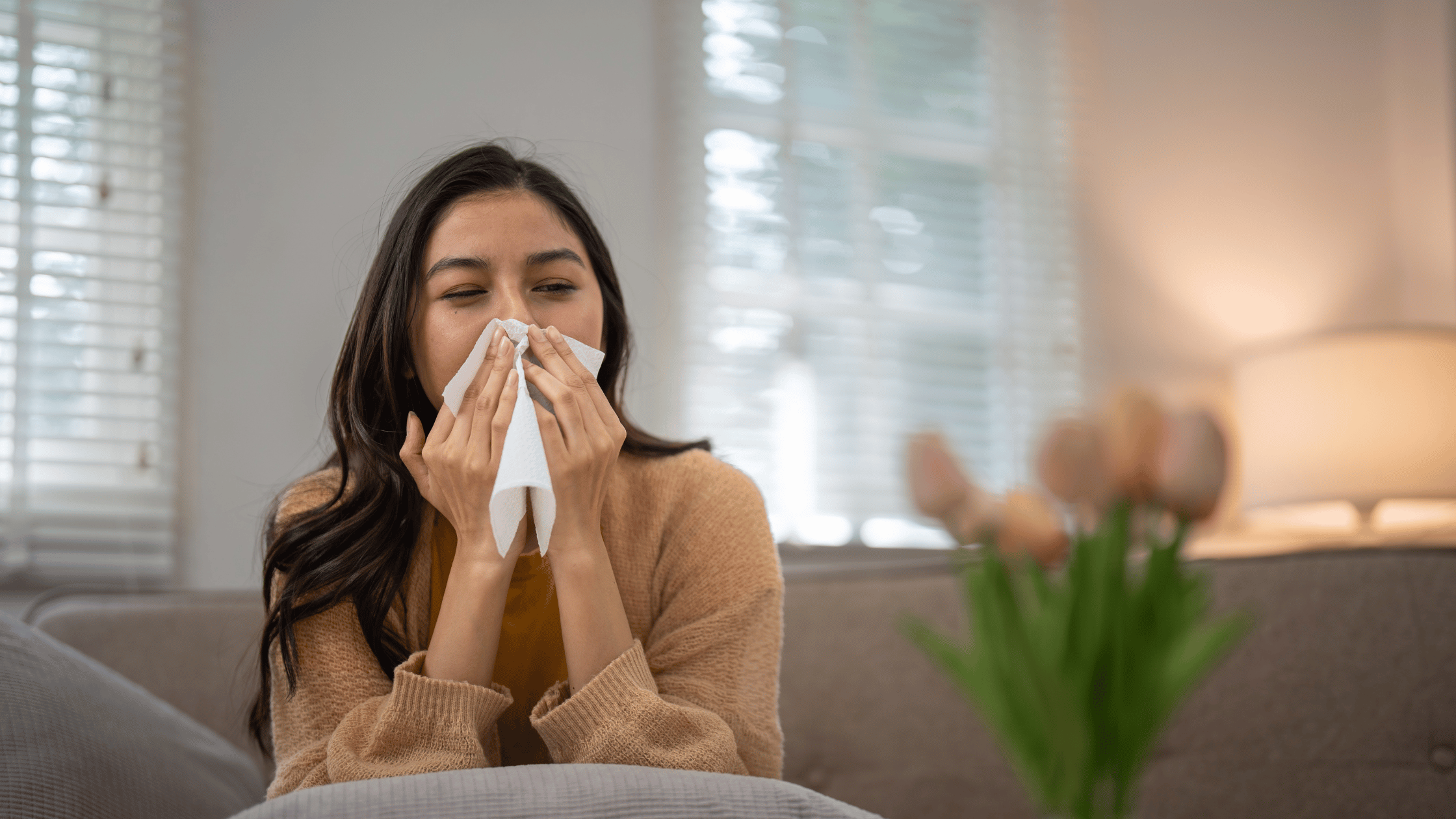 Femme assise sur son divan dans la maison qui éternue en raison de son air intérieur sale