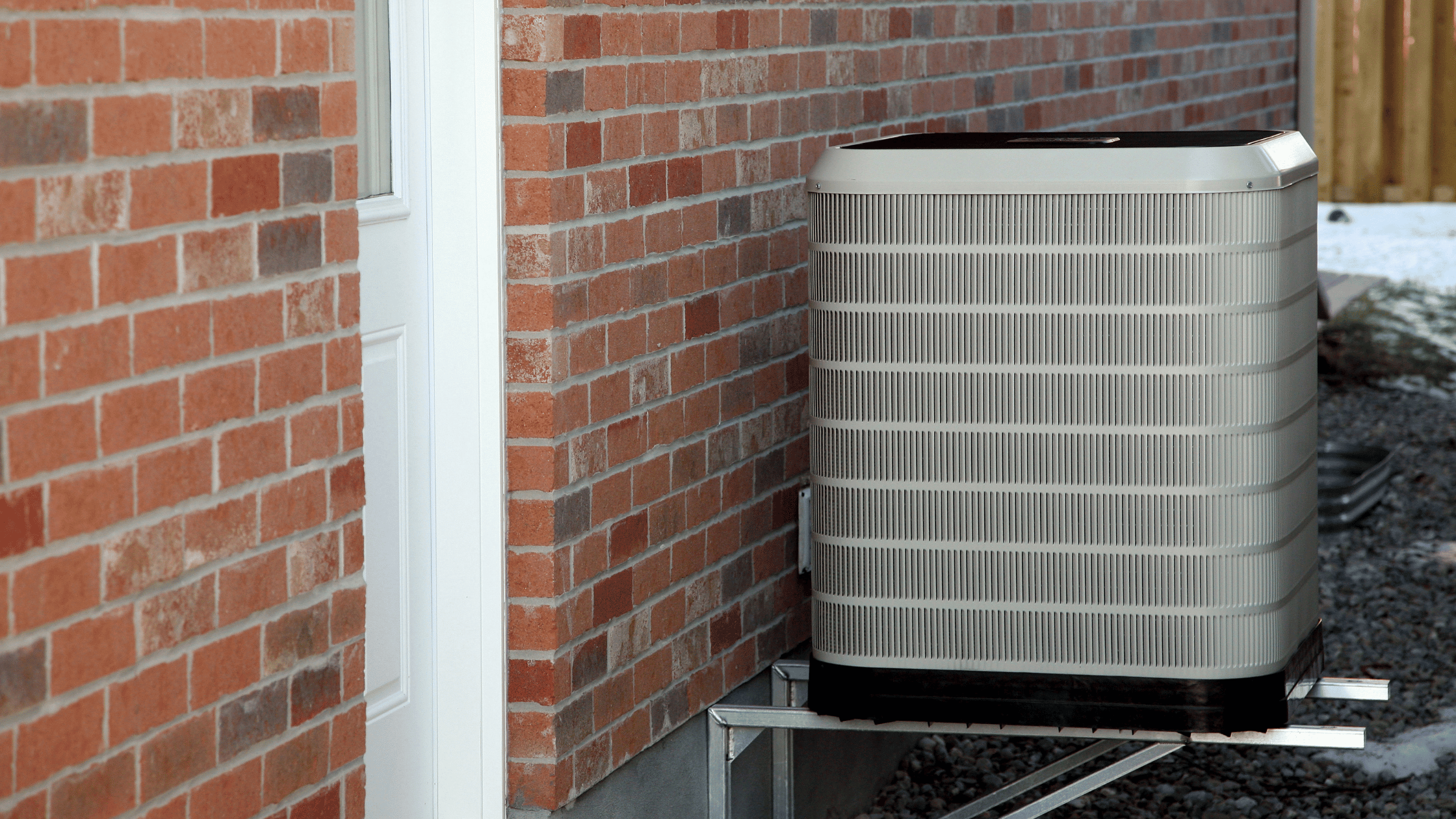 Central heat pump outdoor unit installed on a brick wall