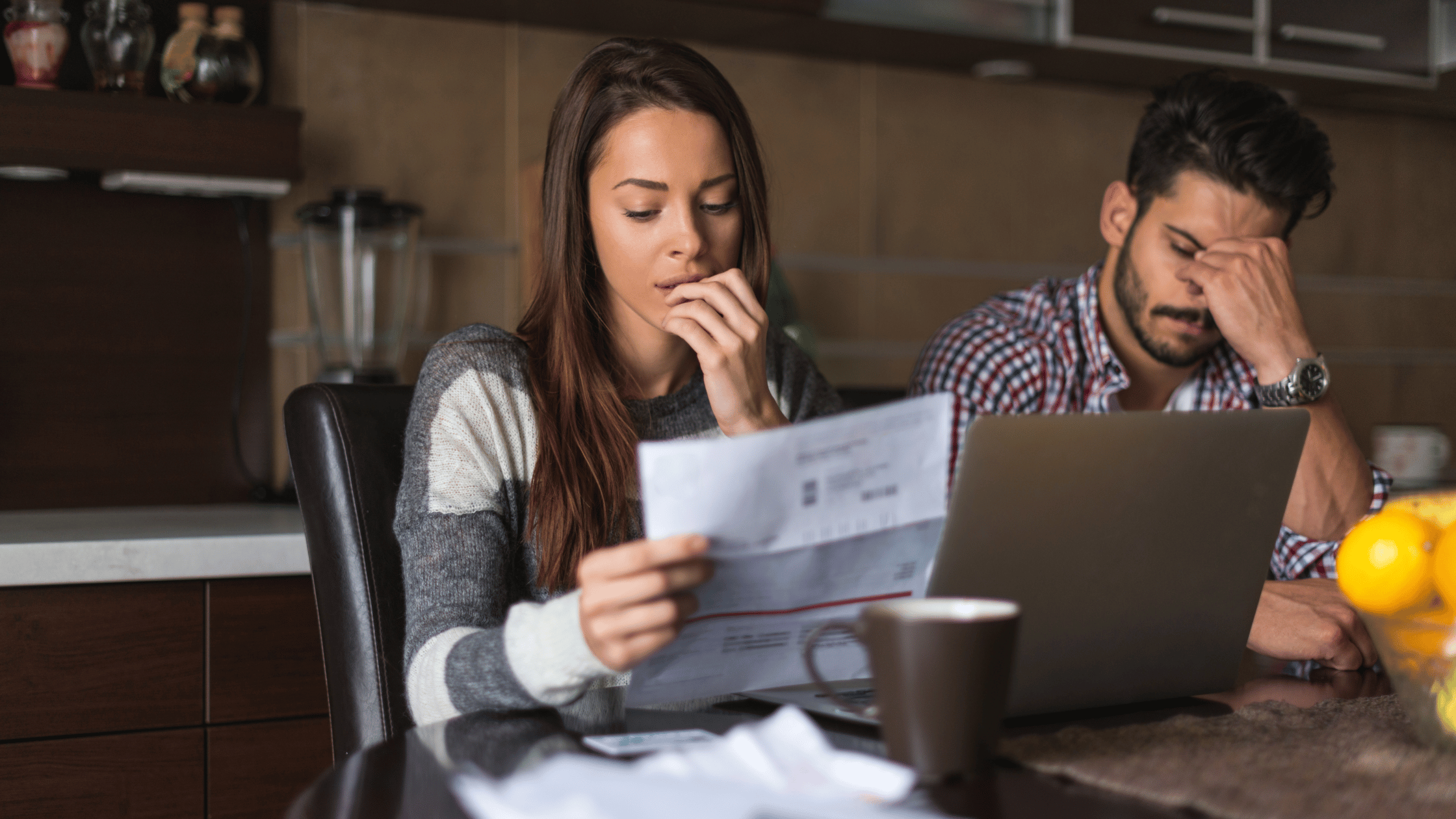 young woman in her thirties looking at her electricity bill with a worried expression