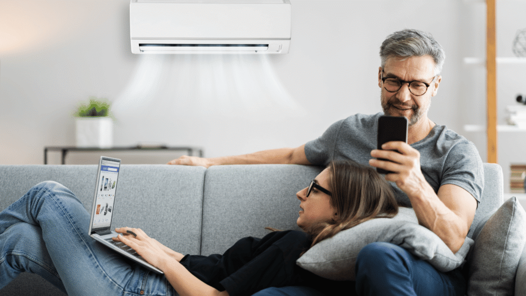 couple sitting on the living room sofa enjoying the cool air from their new heat pump