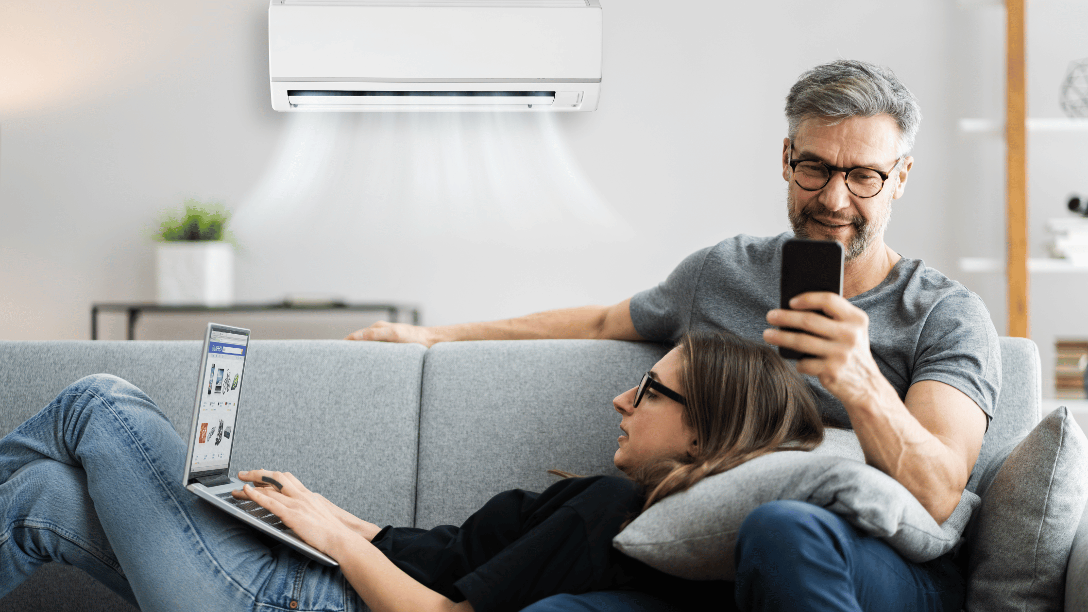 couple sitting on the living room sofa enjoying the cool air from their new heat pump