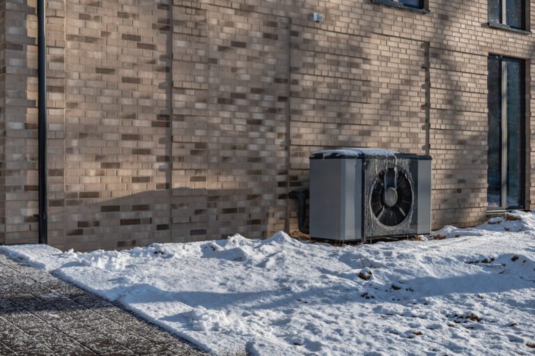 Thermopompe centrale extérieure près d'une maison en hiver