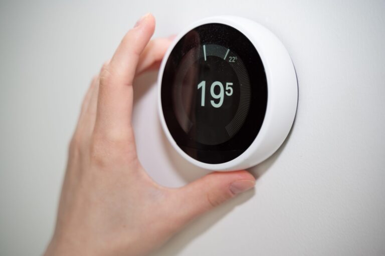 Main qui ajuste un thermostat intelligent